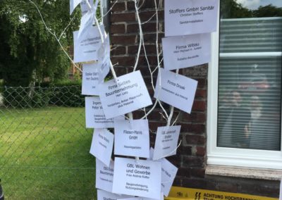 Baum vor der Ladestation mit aufgehängten Zetteln auf denen die Sponsoren stehen